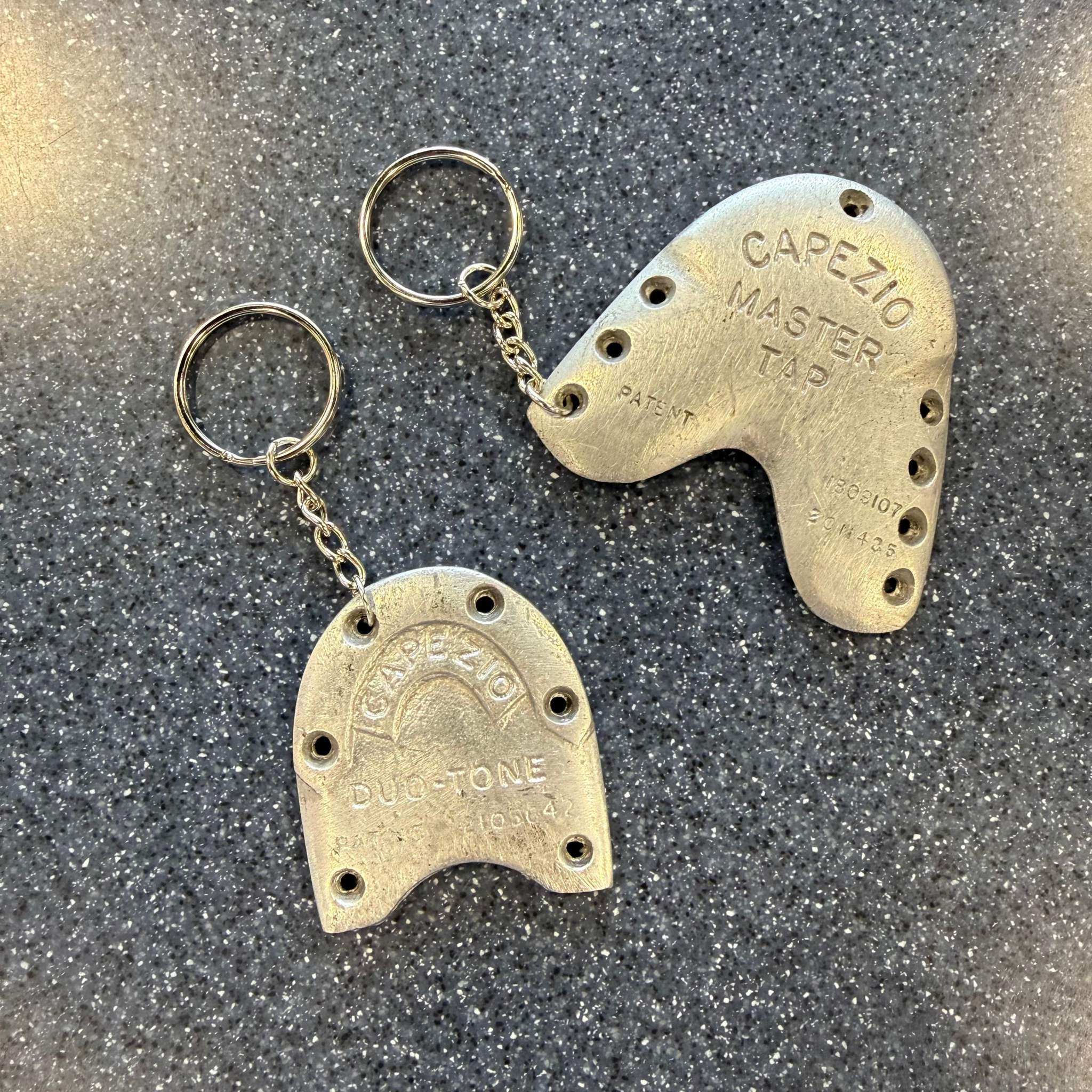 Tap Dance Keychain made from silver metal worn tap shoe parts with engraved text and attached keyring on speckled surface