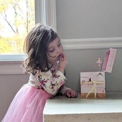 Ballet School Musical Jewelry Box in pastel pink with ballet artwork and a twirling ballerina figurine on top as a young girl watches