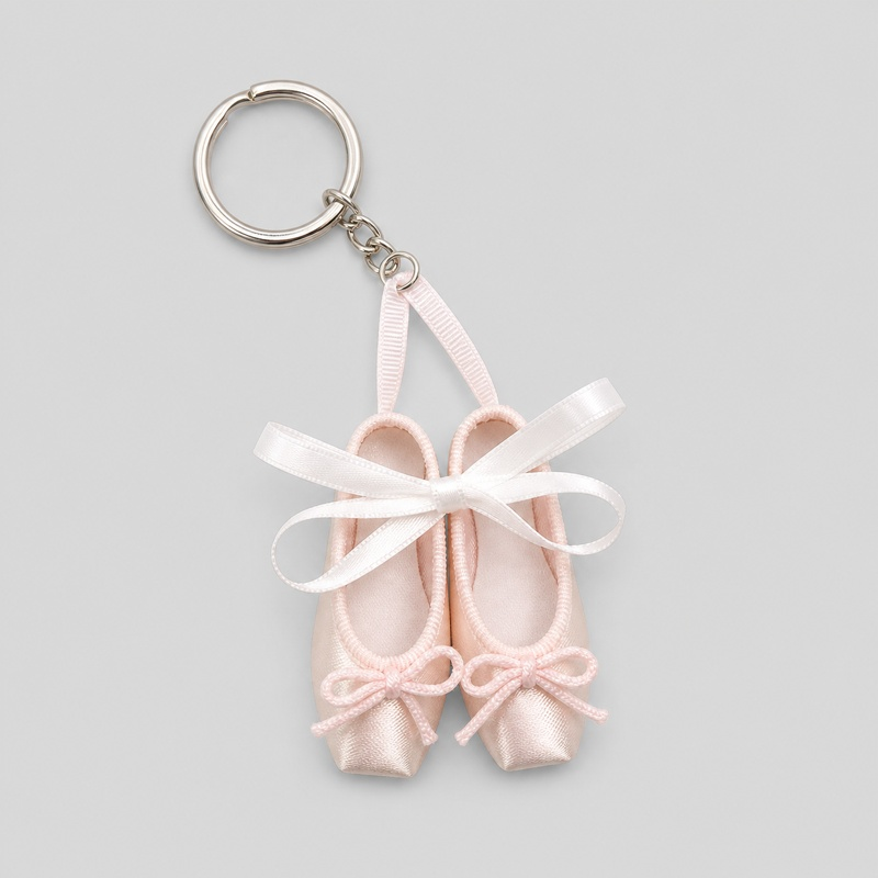 Ballet pointe shoe keychain featuring small pink satin shoes with pink bows and white ribbon tied in a bow
