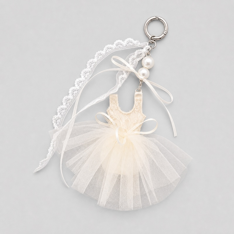 ballet tutu bag charm in cream with lace top, tulle skirt, ribbons, and pearl accents on keyring