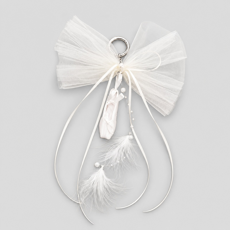 Ballet shoe bag charm featuring white satin ballet slippers, tulle tutu bow, flowing ribbons, and delicate feather accents
