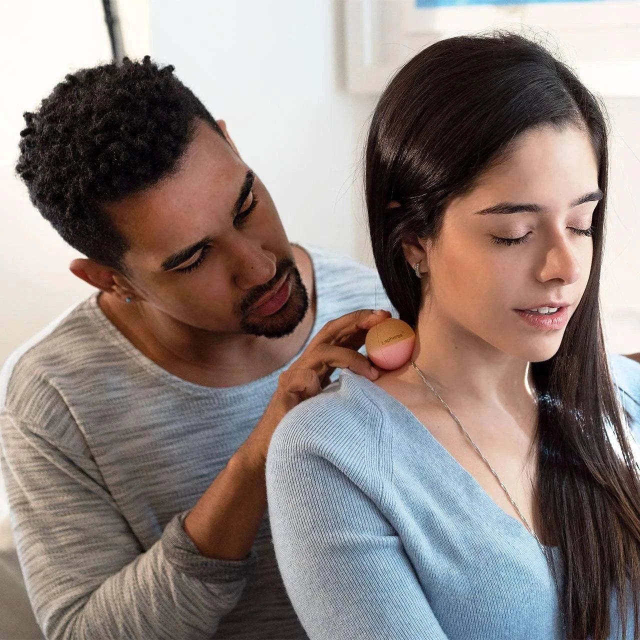 TSpheres Perk Up aromatherapy massage ball in peach color being used on shoulder for muscle relief